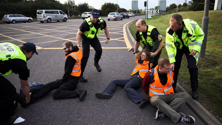 Police officers remove Insulate Britain activists as they block a roundabout at a junction on the M25 motorway during a protest in Thurrock, Britain October 13, 2021. REUTERS/Henry Nicholls
