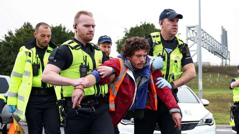 Police officers detain an Insulate Britain activist blocking a roundabout at a junction on the M25 motorway as they a protest in Thurrock, Britain October 13, 2021. REUTERS/Henry Nicholls
