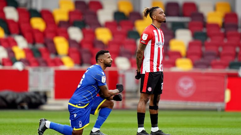 Ivan Toney stands as a rival player takes the knee