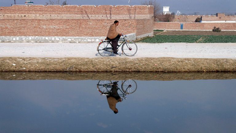 An Afghan man rides his bicycle on the outskirts of Jalalabad, Nangarhar province east of Kabul, Afghanistan, on Tuesday, Dec. 27, 2011. (AP Photo/Rahmat Gul)