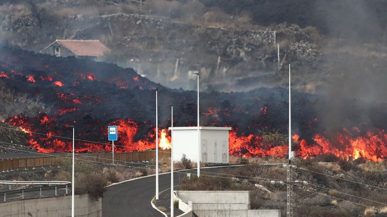 2021年10月13日、スペインのタグイヤから見たカナリア諸島のラパルマ島でクンブレビエハ火山が噴火し続けると、溶岩がロスジャノスの街灯柱の後ろを転がります。ロイター/セルジオペレス