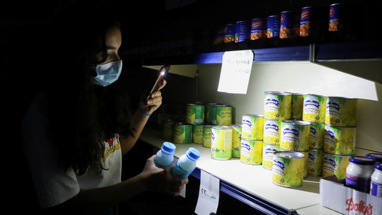 A customer uses her phone&#39;s torch light in a grocery store near the town of Bhamdoun