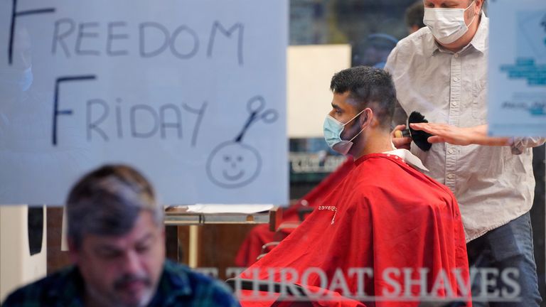 A barber cuts a man&#39;s hair on the first day of eased restrictions
