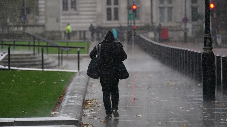 A man walks through a rain shower in central London. Picture date: Friday October 29, 2021.
