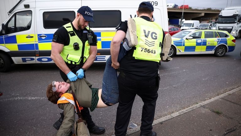 Police officers detain a man as Insulate Britain activists block a roundabout at a junction on the M25 motorway during a protest in Thurrock, Britain October 13, 2021. REUTERS/Henry Nicholls
