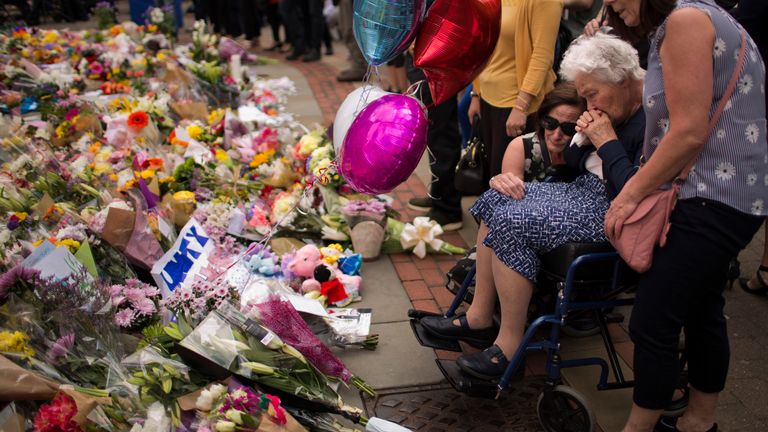 DOSSIER – Dans cette photo d'archive du 24 mai 2017, des femmes pleurent après avoir déposé des fleurs sur une place du centre de Manchester, en Grande-Bretagne, après l'attentat-suicide lors d'un concert d'Ariana Grande qui a fait plus de 20 morts et de nombreuses autres blessées, comme il s'est terminé lundi nuit à la Manchester Arena.  (AP Photo/Emilio Morenatti, Dossier)