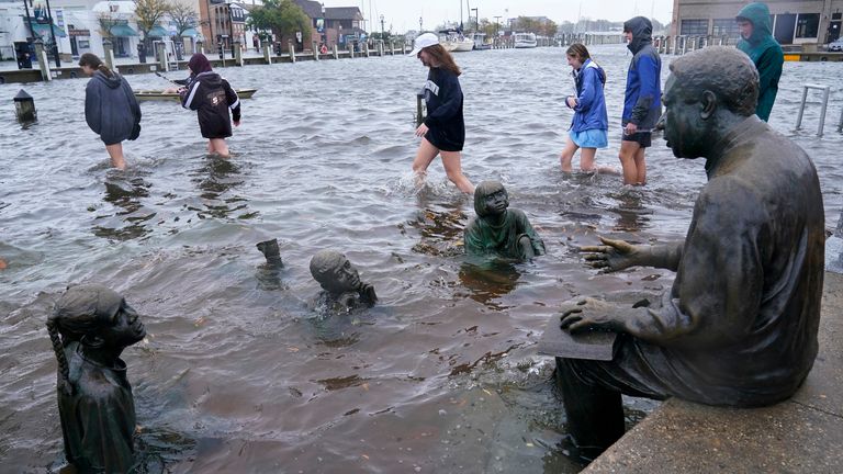 People walk past the Kunta Kinte-Alex Haley Memorial as they survey the flooding in downtown Annapolis, Friday, Oct. 29, 2021. The city is anticipating potential historic tidal flooding conditions in low-lying areas this Friday and Saturday. (AP Photo/Susan Walsh)