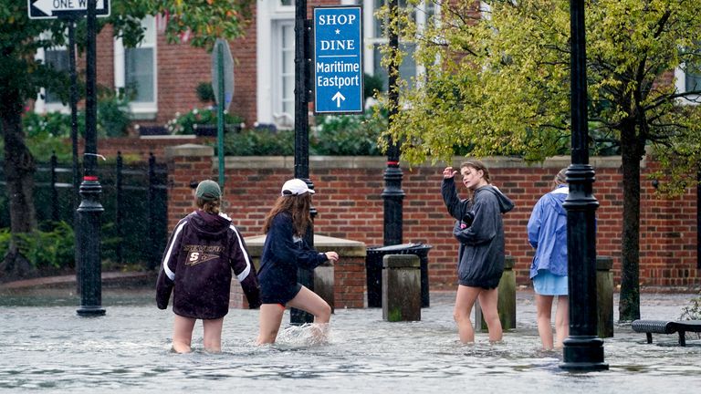 People walks on a flooded sidewalk in downtown Annapolis, Md., Friday, Oct. 29, 2021. The city is anticipating potential historic tidal flooding conditions in low-lying areas this Friday and Saturday. (AP Photo/Susan Walsh)