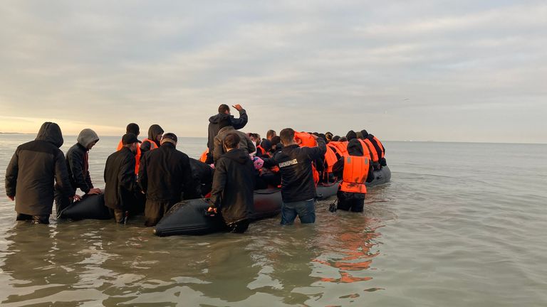 Migrants  - manhandling a large inflatable boat down a northern French beach, to get to the seafront in order to to cross the Channel.  - re copy from  Adam Parsons and Sophie Garratt