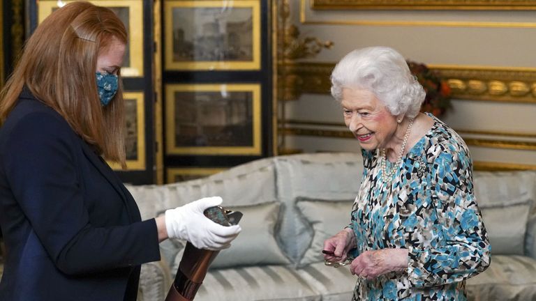 Queen Elizabeth II looks at the Birmingham 2022 Commonwealth Games Baton that will carry a message from her during a relay which starts at Buckingham Palace in London before 7,500 bearers take the baton on a 90,000-mile journey to all 72 nations and territories of the Commonwealth over 294 days. Picture date: Monday October 4, 2021.
