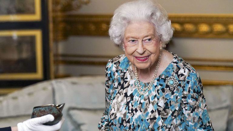 Queen Elizabeth II looks at the Birmingham 2022 Commonwealth Games Baton that will carry a message from her during a relay which starts at Buckingham Palace in London before 7,500 bearers take the baton on a 90,000-mile journey to all 72 nations and territories of the Commonwealth over 294 days. Picture date: Monday October 4, 2021.