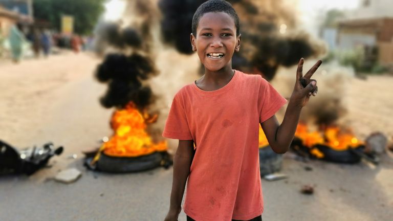 Et barn gestikulerer foran en brennende veisperring under det informasjonsdepartementet kaller et militærkupp i Khartoum, Sudan 25. oktober 2021. REUTERS / El Tayeb Siddig
