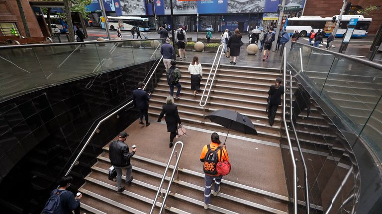 Commuters walk out of an underground train station as people filter into the city after more than 100 days of lockdown to help contain the COVID-19 outbreak in Sydney, Monday, Oct. 11, 2021. (AP Photo/Rick Rycroft)