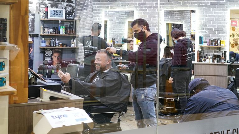 Customers receive haircuts at a city centre barber shop on the first day of many such businesses re-opening to vaccinated patrons, following months of lockdown orders that closed businesses to curb an outbreak of the coronavirus disease (COVID-19), in Sydney, Australia, October 11, 2021. REUTERS/Loren Elliott