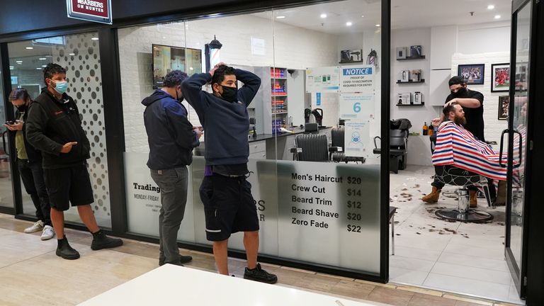 Customers wait in line at a city centre barber shop on the first day of many such businesses re-opening to vaccinated patrons, following months of lockdown orders that closed businesses to curb an outbreak of the coronavirus disease (COVID-19), in Sydney, Australia, October 11, 2021. REUTERS/Loren Elliott