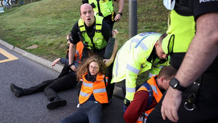 Police officers remove Insulate Britain activists as they block a roundabout at a junction on the M25 motorway during a protest in Thurrock, Britain October 13, 2021. REUTERS/Henry Nicholls
