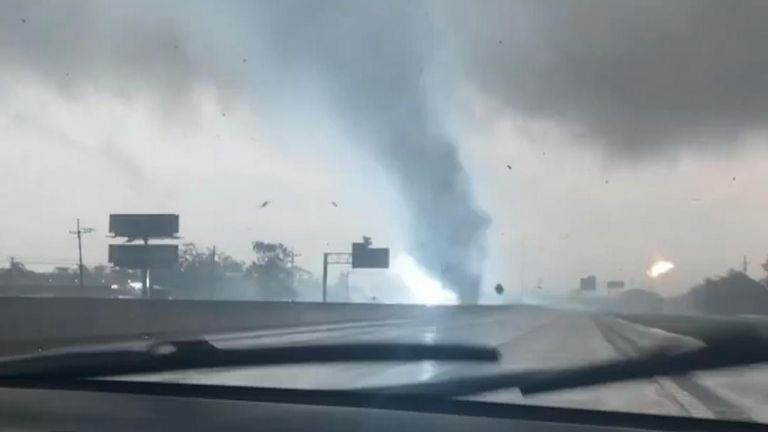 A tornado tore across Interstate 10 in Orange, Texas, whipping up debris and snapping power lines.