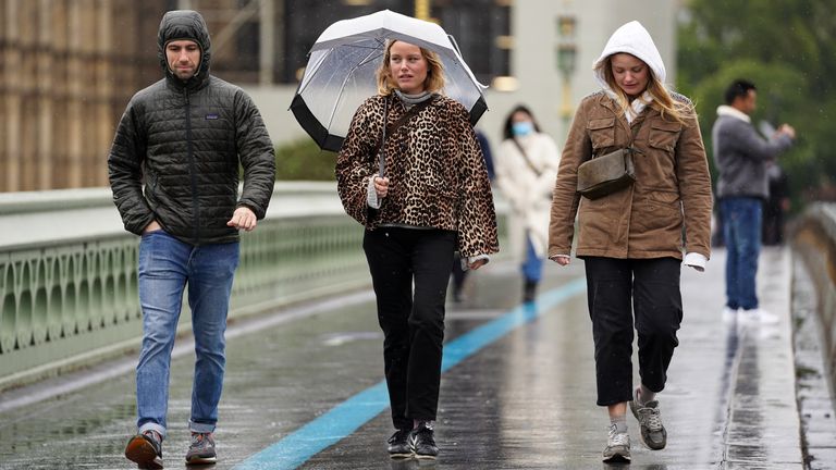 People walk across Westminster Bridge in the rain, in Westminster in London. Heavy rain and strong winds could bring flooding, travel disruption and power outages to parts of England and Scotland over the weekend.