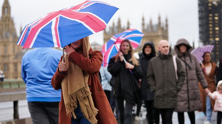 People walk across Westminster Bridge in the rain, in Westminster in London