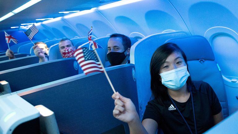 Passengers wearing protective masks hold American and British flags before a JetBlue flight to London at JFK International Airport, 11  August, 2021