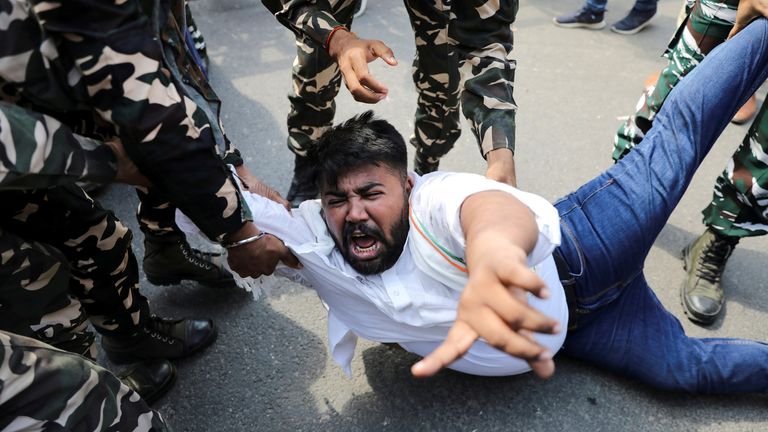 Police forces detain a man during a protest in New Delhi