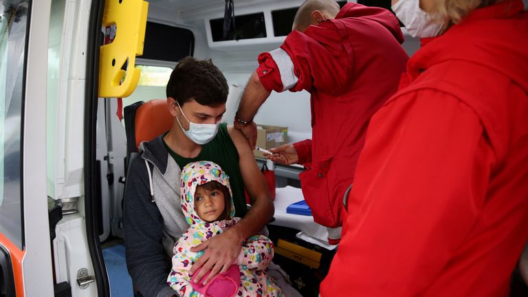 Un homme tient sa fille dans ses bras alors qu'il reçoit une deuxième dose de vaccin contre la maladie à coronavirus (COVID-19) administrée par un personnel médical d'une unité mobile du village de Krushovitsa, en Bulgarie, le 10 octobre 2021. REUTERS/Stoyan Nenov/ Fichier photo