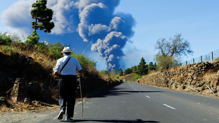 A man walks along an El Paso road while observing a large ash column from the Cumbre Vieja volcano on the Canary Island of La Palma, Spain, October 4, 2021. REUTERS/Borja Suarez
