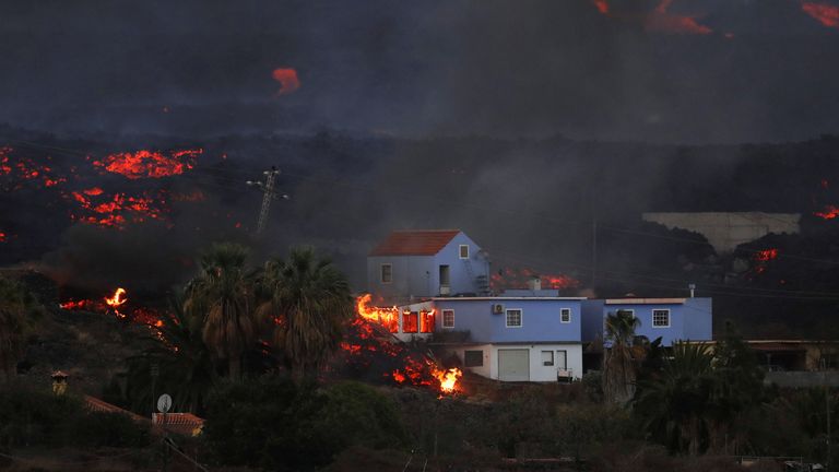 Lava from the Cumbre Vieja volcano burns a house on the Canary Island of La Palma, as seen from Tajuya, Spain, October 19, 2021. REUTERS/Susana Vera
