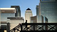 An early morning walker on a bridge in front of the Canary Wharf skyline, in East London.
