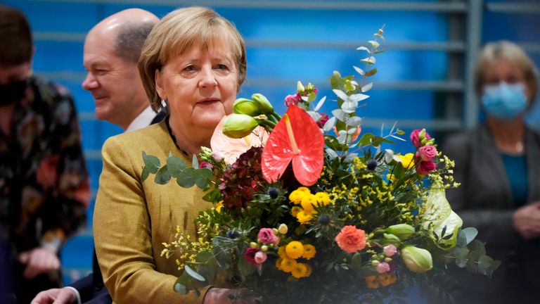 Angela Merkel receives a bouquet of flowers at her final cabinet meeting from Vice Chancellor Olaf Scholz who is expected to replace her as leader. Pic: AP