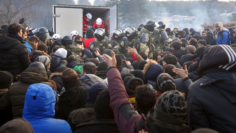 Belarusian troops bring aid to migrants waiting at the border with Poland. Pic: AP