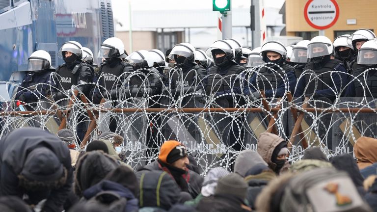 Migrants gather in front of a barbed wire fence at the checkpoint 