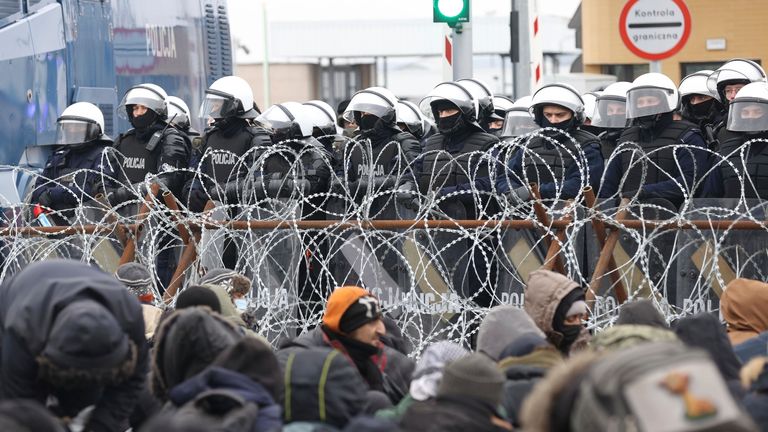 Migranten versammeln sich vor einem Stacheldrahtzaun am Checkpoint "Kusniza" Montag, 15. November 2021 an der weißrussisch-polnischen Grenze bei Grodno, Weißrussland.  Die Außenminister der Europäischen Union werden voraussichtlich am Montag beschließen, die Sanktionen gegen Weißrussland auf Fluggesellschaften, Reisebüros und Einzelpersonen auszudehnen, die angeblich dazu beitragen, Migranten nach Europa zu locken "hybrider Angriff" gegen den Block von Präsident Alexander Lukaschenko.  (Oksana Manchuk / BelTA Poolfoto über AP)