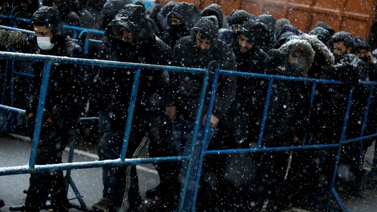 Para migran berjalan selama hujan salju di pusat transportasi dan logistik dekat perbatasan Belarusia-Polandia di wilayah Grodno, Belarus, 23 November 2021. REUTERS / Kacper Pempel