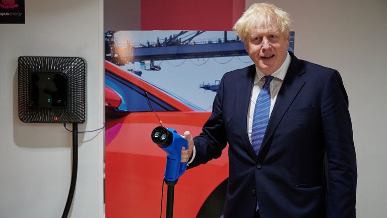 Le Premier ministre Boris Johnson tient un câble de recharge de véhicule électrique lors d'une visite au siège d'Octopus Energy à Londres.