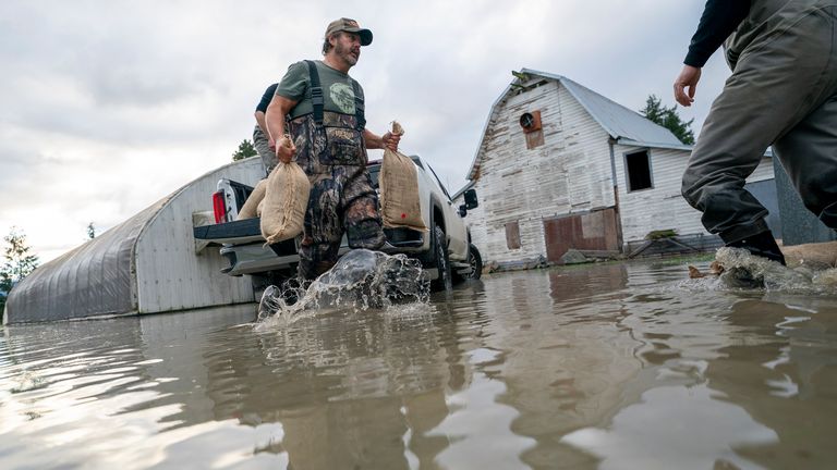 People load sand bags to try and stop the rising flood waters in Barrowtown near Abbotsford, BC. Pic: AP.         