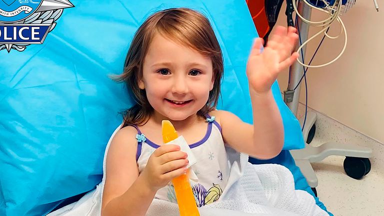 In this photo provided by the Western Australia Police, four-year-old Cleo Smith waves as she sits on a bed in hospital, Wednesday, Nov. 3, 2021, in undisclosed location, Australia. Police smashed their way into a suburban house on Wednesday and rescued Cleo whose disappearance from her family&#39;s camping tent on Australia&#39;s remote west coast more than two weeks ago both horrified and captivated the nation. The seal of Western Australia Police is seen at top left. 
Western Australia Police / AP