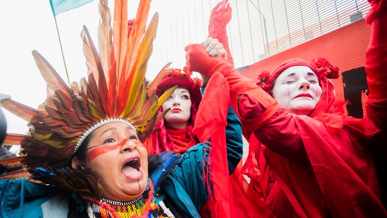 Protesters from indigenous communities and Extinction Rebellion hold hands outside COP26