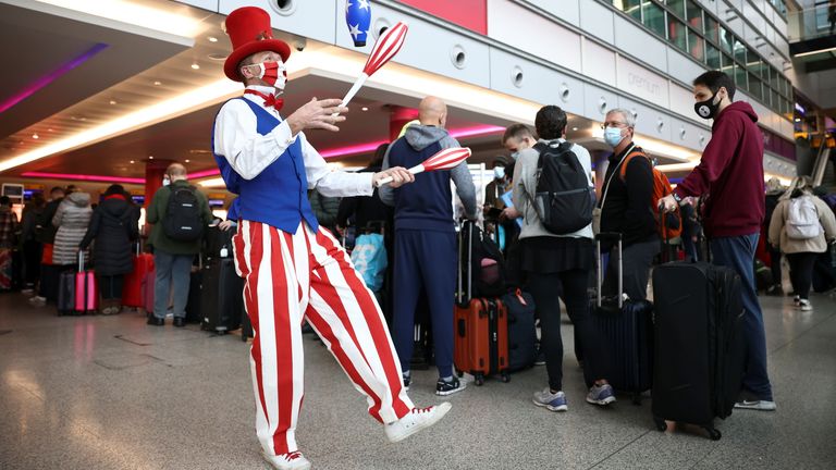 A performer juggles as he engages with travellers while they queue to check into Virgin Atlantic and Delta Air Lines flights at Heathrow Airport Terminal 3, following the lifting of restrictions on the entry of non-U.S. citizens to the United States imposed to curb the spread of the coronavirus disease (COVID-19), in London, Britain, November 8, 2021. REUTERS/Henry Nicholls
