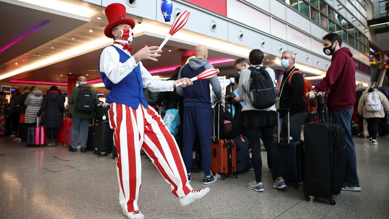 A performer juggles as he engages with travellers while they queue to check into Virgin Atlantic and Delta Air Lines flights at Heathrow Airport Terminal 3, following the lifting of restrictions on the entry of non-U.S. citizens to the United States imposed to curb the spread of the coronavirus disease (COVID-19), in London, Britain, November 8, 2021. REUTERS/Henry Nicholls
