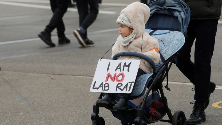 Une pancarte est accrochée à un enfant alors que les gens protestent contre une loi du gouvernement suisse sur la maladie à coronavirus (COVID-19), à Zurich, en Suisse, le 20 novembre 2021