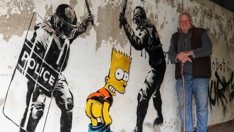 Darrell Meekcom poses next to the image of Bart Simpson which appeared after he was arrested for mooning a speed camera. Pic: SWNS