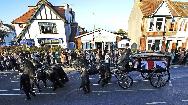 Members of the public pay their respects as the horse drawn hearse carrying the coffin of Sir David Amess, arrives at his constituency office at Iveagh Hall, in Leigh-on-Sea, following his funeral service. Picture date: Monday November 22, 2021.