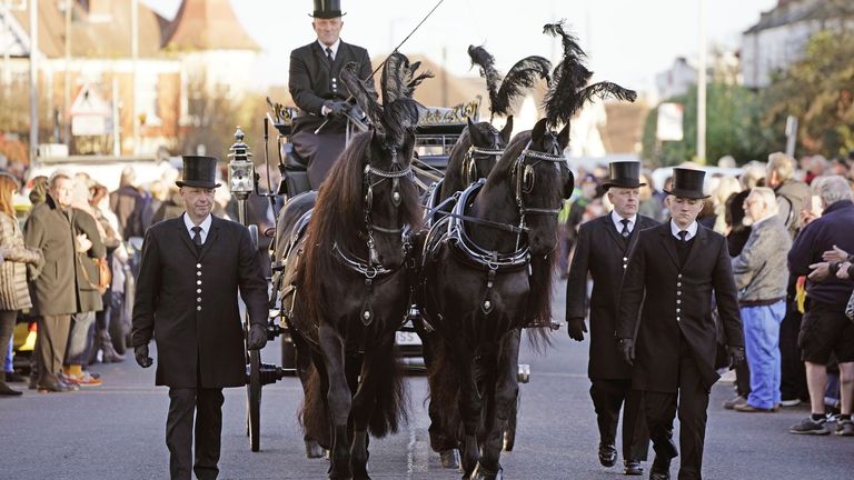 Members of the public pay their respects as the horse drawn hearse carrying the coffin of Sir David Amess, arrives at his constituency office at Iveagh Hall, in Leigh-on-Sea, following his funeral service. Picture date: Monday November 22, 2021.