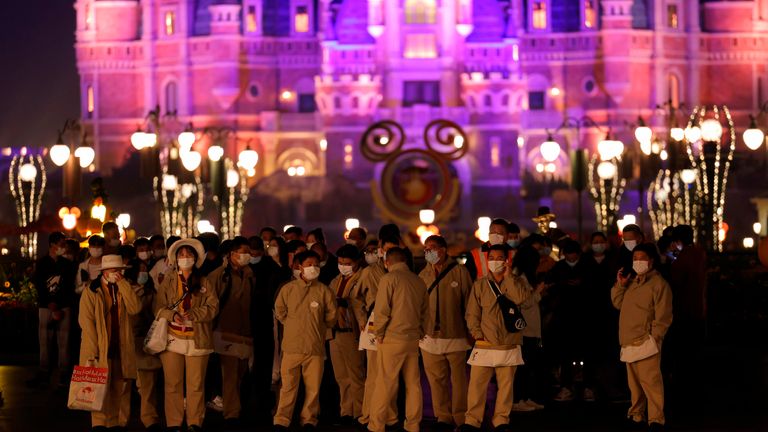 Disneyland workers wait to be tested for Covid-19 as the castle is seen in the background in Shanghai, China late Sunday, Oct. 31, 2021. A visitor to the popular theme park was found Sunday contracted with Covid-19. Over 30,000 people were tested before leaving the park, which will be closed for two days.