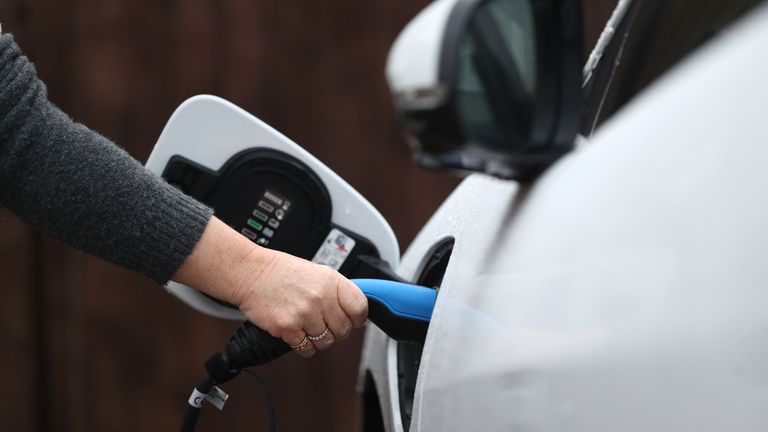 An electric charging cable connected to a Jaguar I-Pace electric car at a residential home.
