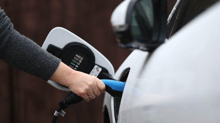 An electric charging cable connected to a Jaguar I-Pace electric car at a residential home. 