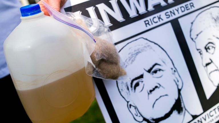 A resident protests in 2016 with a jug of her tap water and bag containing hair she lost. File pic: AP