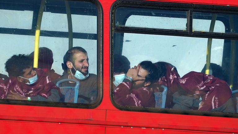 A group of people thought to be migrants wait on a holding bus after being brought in to Dover, Kent