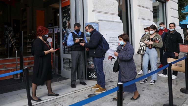 A shop employee checks customers’ vaccination certificates against the coronavirus disease (COVID-19), as the government imposed further measures for unvaccinated citizens, in Athens, Greece, November 22, 2021. REUTERS/Louiza Vradi
